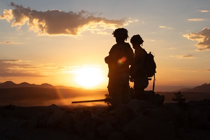 silhouette of two soldiers standing with sunset in background