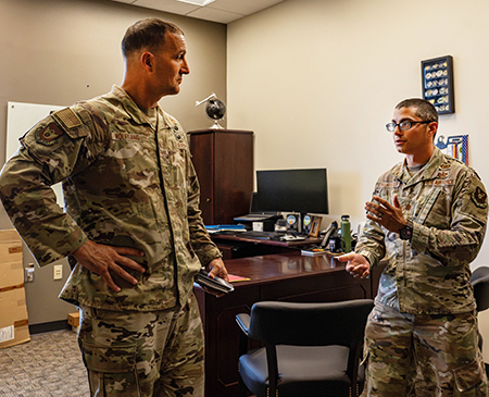Photo of two USAF airmen having a conversation in an office setting.