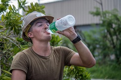 Builder 3rd Class drinks water while reconstructing a roof for a home that was damaged during Typhoon Mangkhut