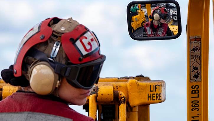 Image of Aviation Ordnanceman 3rd Class Dominique Campbell drives a forklift on the flight deck of the Nimitz-class aircraft carrier USS Harry S. Truman (CVN 75) during a vertical replenishment. She is wearing proper hearing and vision protection.