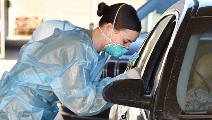 Image of Soldier wearing protective gear leaning into a car to chat with other soldier.