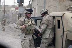 Two army men standing next to a military vehicle