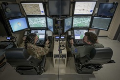 U.S. Air Force Capt. Danielle ‘Dani’ Pavone, an MQ-9 pilot with the 110th Wing, speaks during a training scenario through a plexiglass barrier to Staff Sgt. Justin Brandt, an MQ-9 sensor operator at the Battle Creek Air National Guard Base, Battle Creek, Michigan. The plexiglass mitigates risk of coronavirus transmission during the pandemic. (U.S. Air National Guard photo by Staff Sgt. Bethany Rizor)