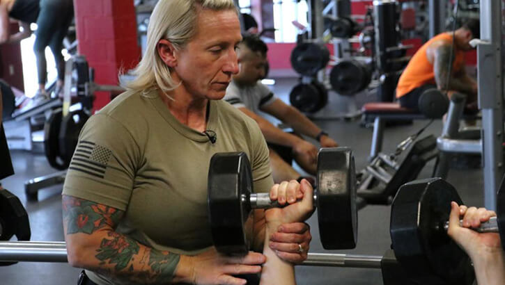 Image of A woman helps a person lifting weights.