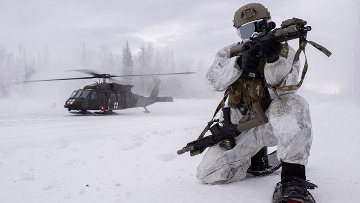 Image of A special tactics airman provides security while an Alaska Army National Guard Black Hawk helicopter lands behind him during an arctic training exercise at Camp Mad Bull, Joint Base Elmendorf-Richardson, Alaska, on Jan. 10, 2023. Appropriate cold weather gear, nutrition, and training are essential for safety in cold, windy and wet conditions. (Photo by Alejandro Pena, U.S. Air Force).