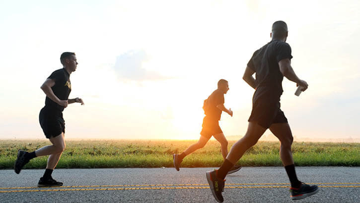 Image of Three soldiers running on blacktop road in the country.