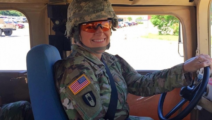 Image of Military personnel posing for a picture while driving a truck.