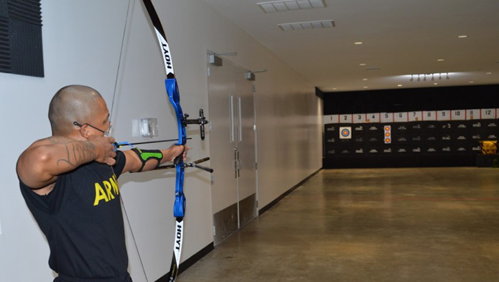 Image of Picture of military personnel wearing a face mask and shooting a bow and arrow.