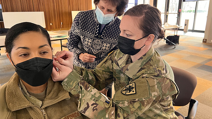 Image of Dr. Arnyce Pock, associate dean and medical acupuncturist at USU, oversees graduate nursing students at USU performing battlefield acupuncture for pain management, in February 2022. The course is intended to train health care personnel who are not physicians or acupuncturists, such as advanced practice nurses, to provide BFA to patients for pain management. (Photo: Uniformed Services University of the Health Sciences).