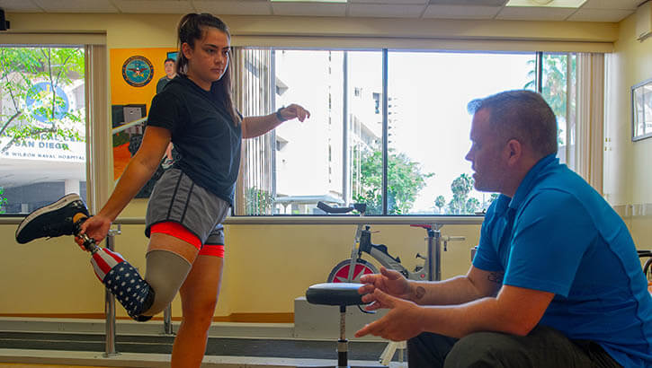 Image of U.S. Marine LCpl. Annika Hutsler works with James Malinak, a prosthetician at Naval Medical Center San Diego’s Comprehensive Combat and Complex Casualty Care clinic to adjust her prosthetic leg. C5 serves to deliver multidisciplinary, quality health services in an outpatient rehabilitation facility for wounded, ill, and injured service members. (Photo: U.S. Navy Mass Communication Specialist 3rd Class Jake Greenberg).