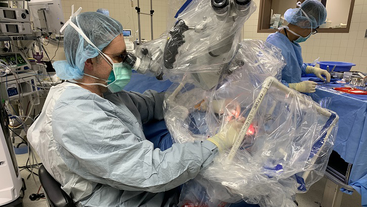 Image of Two medical personnel, wearing full PPE, in an operating room.