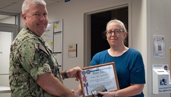 Ms. Krista Fries posing with military personnel with a certificate