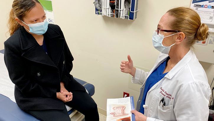 Image of A patient sits in an office with while a health care provider talks to her.