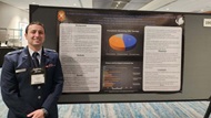 A Hematology Medical Oncology fellow stands in front of his research poster at a conference.   