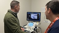 A fellow performs an extremity ultrasound on a resident. 