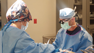 A physician performs ophthalmologic surgery with a technician assisting during the procedure. 