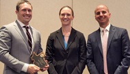 An Orthopaedic resident smiles as he receives an award at OMER Day 2023 presented by two sports faculty members. 