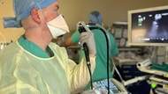 A fellow performs bronchoscopy on a patient.