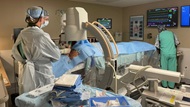 A team of physicians perform bronchoscopy with aid of fluoroscopy.