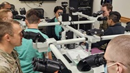 Resident instructs fellow residents on the fine points of a complex cytology case at the multi-head microscope. Microscopic image can be seen projected onto screen behind presenter.