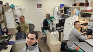 A cubical of residents at their personal desks taking a break from examining slides on their individual microscopes. 