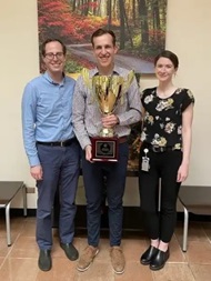 Psychiatry residents proudly displaying the trophy as victorious champions of the national American Psychiatric Association Mind Games competition.