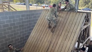 Interns complete a challenge involving climbing an incline using rope at the Leadership Reaction Course at Camp Bullis. 