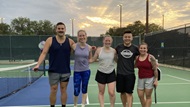 Interns standing together at a tennis court. 