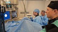 a faculty staff and a technician are watching a urology resident performing a surgical procedure. 