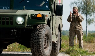 Link to Photo: A Ukrainian Soldier uses hand signals during a ground guide exercise of field litter ambulance familiarization on the driving range at Yavoriv Training Area, Ukraine. A team of medics and a mechanic from 557th Medical Company and 212th Combat Support Hospital are working together to conduct field littler ambulance and medical equipment  familiarization with the Ukrainian military. (U.S. Army photo by Capt. Jeku)