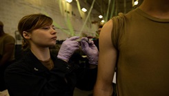 Image of a woman giving someone an injection on the arm.