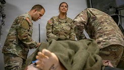 Army combat medic specialists assigned to the 101st Airborne Division, perform simulated casualty care on a mannequin as part of training 