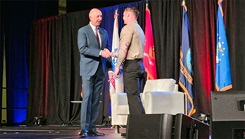Dr. Stephen L. Ferrara, acting Assistant Secretary of Defense for Health Affairs, presents a coin to U.S. Navy Hospital Corpsman 1st Class Jonathan Shumaker. The Uniformed Services University’s recognitions and contributions at the 2025 MHS Conference