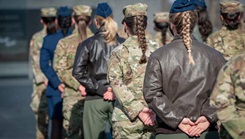 Female Airmen stand at parade rest.