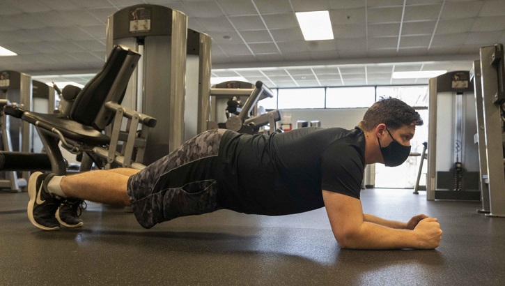 Image of Military personnel wearing a mask exercising in the gym.