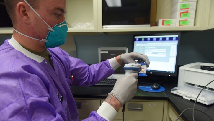 Image of Military health personnel wearing a face mask prepares COVID-19 test samples.