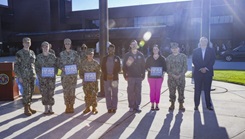 Naval Medical Center Camp Lejeune Director/Commander Capt. Anja Dabelić (far left) and Mr. Charles White, HonorBridge representative (far right), join Naval Medical Center Camp Lejeune employees with the Transfer Center, Intensive Care Unit, and nursing teams to receive the “Guiding Light Award” on Aug. 22, 2024.