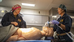 Military medical personnel performing mock surgery on a mannequin