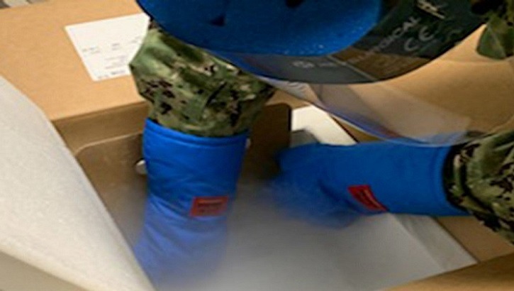 Image of Gloved hands preparing vaccine for transportation.