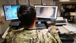 HN Milo Devore, a corpsman at Medical Home Port, demonstrates a physical assessment using the Telehealth Medical Cart, which enables real-time image sharing for remote provider evaluations