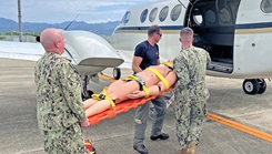 Navy Lt. Alexander Johnson and Petty Officer 3rd Class Evan Talcott, assigned to Navy Medicine Readiness and Training Command Yokosuka, Japan, transfer a simulated casualty to a C-12 Huron aircraft at Nagasaki Airport during a mass casualty drill