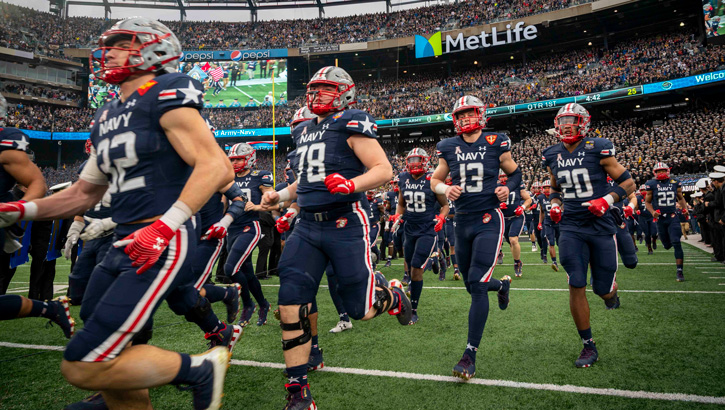 Image of Naval Academy football team runs onto the field .