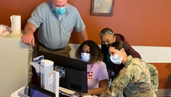 Military personnel looking at a computer