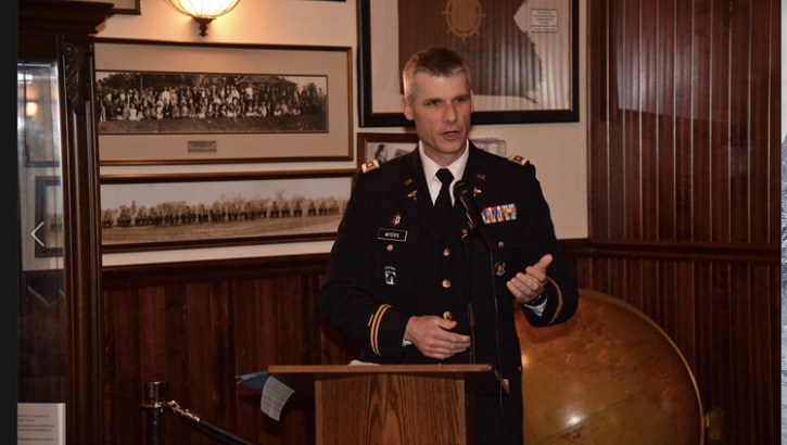 Image of Military personnel speaking at a podium.