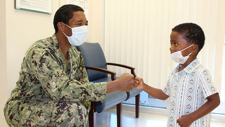 Image of A man fist bumps a child.