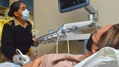 A certified nurse midwife performs an ultrasound on a patient