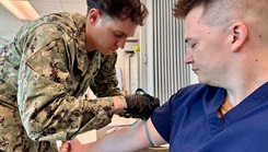 Hospital Corpsman 2nd Class Clayton VanStry demonstrates the process to collect fresh whole blood from Hospital Corpsman 3rd Class Joshua Moulton at U.S. Naval Hospital Guantanamo Bay