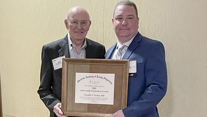 Image of Two men pose with an award.