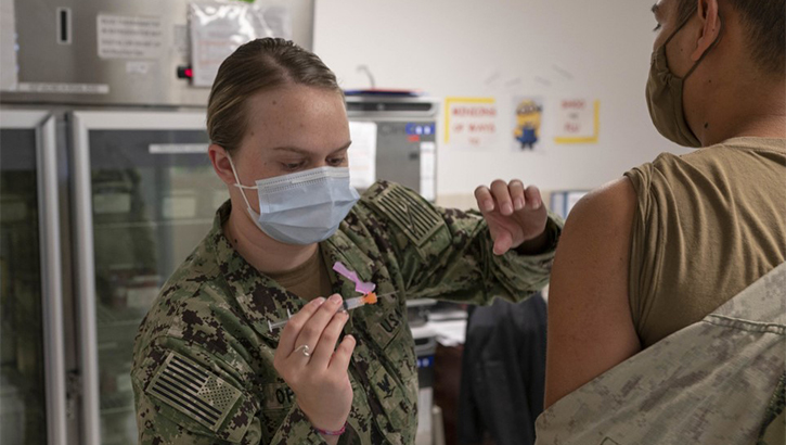 Image of Military personnel wearing a face mask receiving the COVID-19 vaccine.