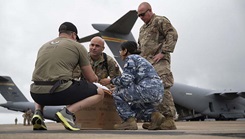 A U.S. Special Operations Forces Operator retrieves a cold chain blood resupply shipment from U.S. Army Sgt. 1st Class Eric Jimenez, medical logistics noncommissioned officer; Royal Australian Air Force Flt. Lt. Pooja Sapkota, scientific officer and pathology advisor, both with the Combined Joint Theatre Medical Component; and a member of the U.S. Air Force’s C-17 Globemaster crew, 535th Airlift Squadron, in Queensland, Australia, during Exercise Talisman Sabre 2025 on July 22, 2025. (U.S. Army photo illustration by Sgt. 1st Class Timothy Hughes.)